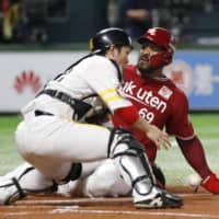 Jabari Blash (right) slides home past Hawks catcher Takuya Kai during the second inning of their game on May 2 at Yafuoku Dome in Fukuoka. Rakuten won 9-0.