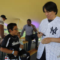 Retired Yankees star Hideki Matsui signs a ball for a young fan during a private baseball clinic in London on Thursday. The Yankees, in town to play the Boston Red Sox, are hosting approximately 100 youth in conjunction with the London Meteorites Baseball and Softball Club.