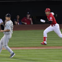 The Angels' Shohei Ohtani (right) runs to first for a single as Mariners starting pitcher Yusei Kikuchi runs to back up the first baseman on Saturday in Anaheim, California.