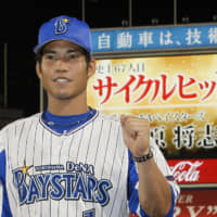 The BayStars' Masayuki Kuwahara poses for photos after hitting for the cycle on July 20, 2018. His achievement is shown on the scoreboard message behind him.