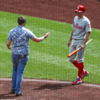The Phillies' Brad Miller backs away as he's approached by a man on the field during Philadelphia's game against the Pirates on Sunday in Pittsburgh.