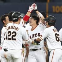The Giants' Shinnosuke Shigenobu (center) celebrates with teammates after hitting a sayonara double in the ninth inning on Tuesday against the Swallows at Kyocera Dome. Yomiuri defeated Tokyo Yakult 6-5.