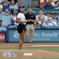 Naomi Osaka prepares to throw the ceremonial first pitch as Dodgers pitcher Kenta Maeda squats behind home plate before a game between the Dodgers and Angels on Wednesday at Dodger Stadium.
