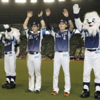 Seibu's Shuto Tonosaki (second from left) and Sosuke Genda (second from right) greet fans after Sunday's win over the Buffaloes at MetLife Dome.