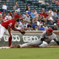 Los Angeles designated hitter Shohei Ohtani slides into third base with a triple ahead as Texas' Danny Santana waits for the throw in the second inning on Monday night.