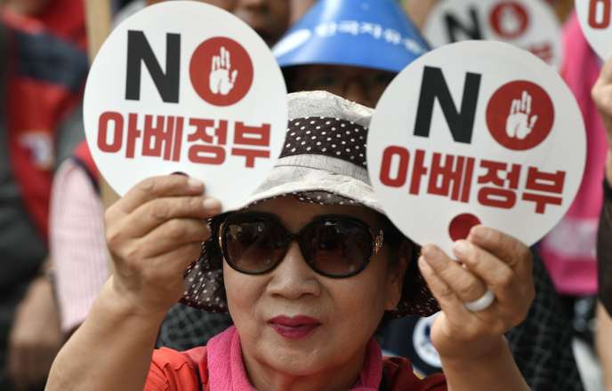 Une manifestante sud-coréenne brandit des pancartes portant la mention « Le gouvernement de M. Abe » lors d’un rassemblement anti-japonais dans le centre de Séoul le 13 août.