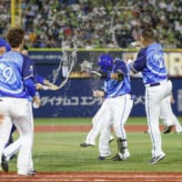 The BayStars' Toshiro Miyazaki has water thrown on him by teammates after his sayonara single against the Swallows on Wednesday in Yokohama.