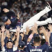 The Lions players toss manager Hatsuhiko Tsuji into the air for the traditional doage after their 12-4 victory over the Marines on Tuesday night in Chiba. Seibu clinched the Pacific League pennant for the second straight year.