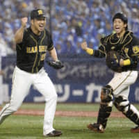 Tigers closer Kyuji Fujikawa (left) and catcher Ryutaro Umeno celebrate after clinching the final out against the BayStars on Monday at Yokohama Stadium.