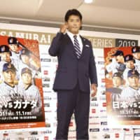 Japan manager Atsunori Inaba on Tuesday stands next to promotional posters for upcoming warmup games against Canada in Okinawa before the Premier12 tournament.
