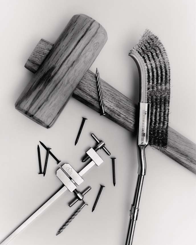 Un marteau en bois, pour les tâches délicates de menuiserie, un pied à coulisse et une brosse antirouille en métal.