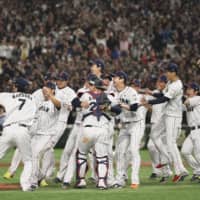 Samurai Japan players celebrate on the mound after beating South Korea to win the Premier12 title on Sunday at Tokyo Dome.
