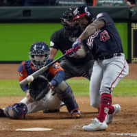 Washington's Howie Kendrick hits a two-run home run against the Astros during Game 7 of the World Series on Oct 30, in Houston. Kendrick and teammate Yan Gomes have re-signed with the Nationals for their 2020 title defense.