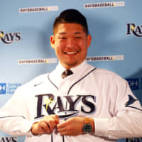 New Tampa Bay player Yoshitomo Tsutsugo puts on a Rays jersey during his introductory news conference on Tuesday in St. Petersburg, Florida.