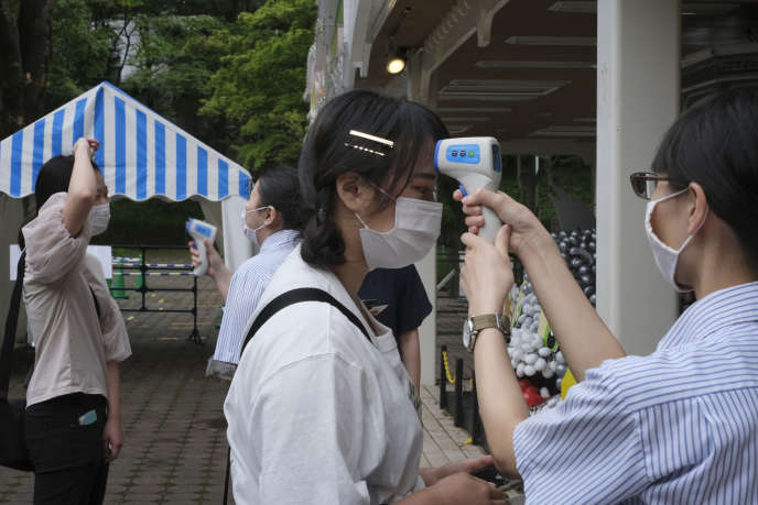 Prise de température des visiteurs, à l’entrée du parc de loisirs Toshimaen, à Tokyo, le 13 juillet.