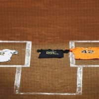 A Black Lives Matter T-shirt is draped across home plate between an Oakland Athletics jersey (left), laid by Marcus Semien, and a Houston Astros jersey, laid by Martin Maldonado, both bearing the No. 42 in honor of Jackie Robinson. | AP