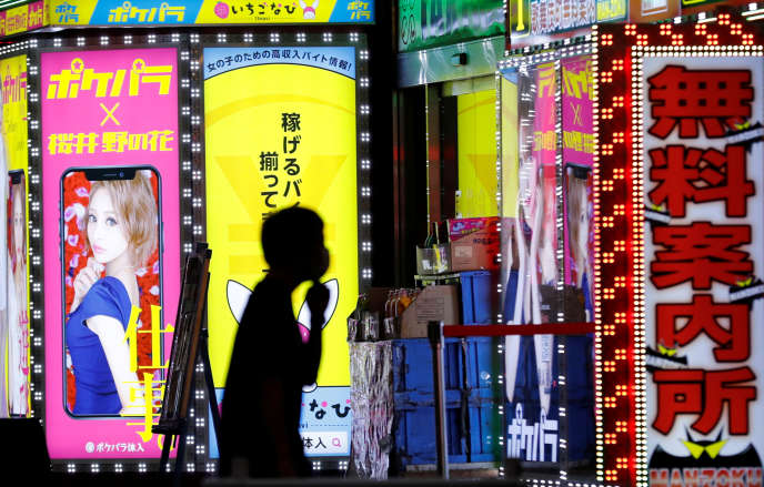 Un homme passe devant une enseigne d’un bar du quartier de Kabukicho, à Tokyo, le 14 juillet.