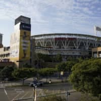 People walk past Petco Park in San Diego, where the Padres and Mariners had been scheduled to play on Tuesday night. | AP