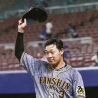 Tigers infielder Yusuke Oyama tips his cap to the crown after his teams win over the Dragons on Friday in Nagoya. | KYODO
