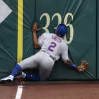 The Mets' Dominic Smith smashes into the outfield wall while chasing a fly ball that went for an inside-the-park home run by Washington's Andrew Stevenson during the first game of a doubleheader on Saturday in Washington. | AP