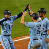 Blue Jays catcher Danny Jansen (left) celebrates his grand slam against the Yankees with teammate Travis Shaw (center) on Monday in Buffalo, New York. | USA TODAY / VIA REUTERS