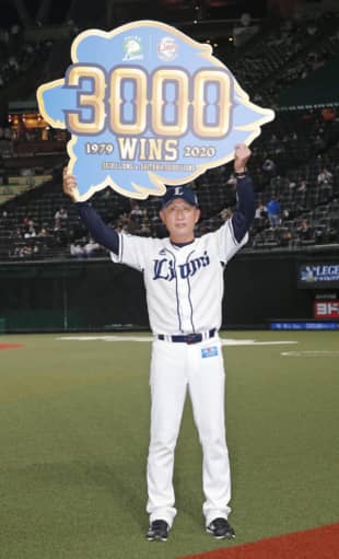 Lions manager Hatsuhiko Tsuji holds a signboard celebrating the team's 3,000th win since moving to Tokorozawa, Saitama Prefecture. | KYODO