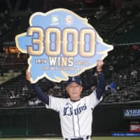 Lions manager Hatsuhiko Tsuji holds a signboard celebrating the team's 3,000th win since moving to Tokorozawa, Saitama Prefecture. | KYODO