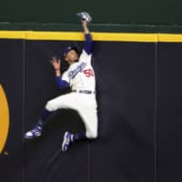 Dodgers right fielder Mookie Betts makes a leaping catch to take a home run away from the Braves' Freedie Freeman during Game 7 in the NLCS on Sunday in Arlington, Texas. | AP