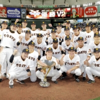 Giants captain Hayato Sakamoto holds the trophy as Yomiuri players pose for photos on the mound after winning the Central League title on Friday. | KYODO