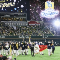 The Hawks carry the Pacific League pennant around PayPay Dome on Tuesday in Fukuoka. | KYODO