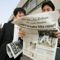 People in the Ginza shopping district of Tokyo read an extra edition of the International Herald Tribune following Ichiro Suzuki's record-breaking hit on Oct. 2, 2004. | REUTERS