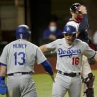The Dodgers' Will Smith (right) celebrates with Max Muncy after hitting a three-run home run against the Braves on Friday in Arlington, Texas. | AP
