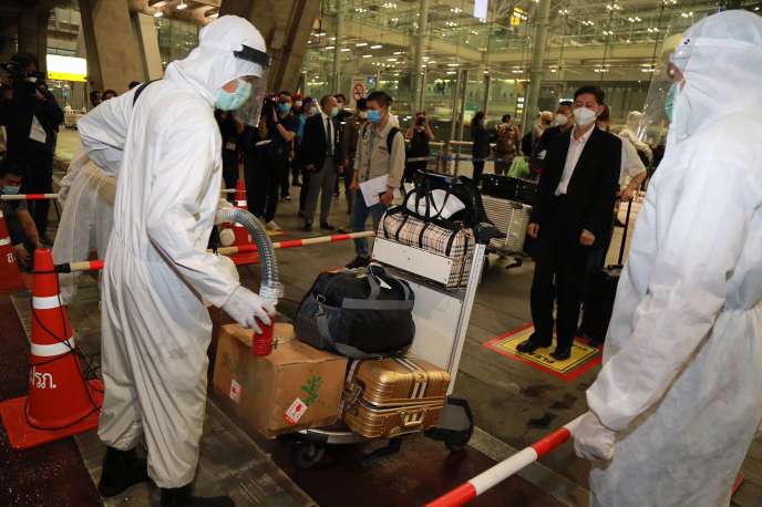 Les bagages d’un groupe de visiteurs chinois sont nettoyés pour arrêter la propagation du Covid-19, à l’aéroport de Suvarnabhumi, à Bangkok, le 20 octobre 2020. Ces voyageurs feront ensuite un séjour de quatorze jours dans un centre de quarantaine d’Etat.