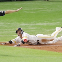 Hawks catcher Takuya Kai slides into first base as the tiebreaking run scores with two outs in the eighth inning during Game 1 of the PL Climax Series on Saturday in Fukuoka. | KYODO
