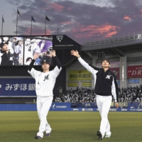 The Marines' Yudai Fujioka (left) and Yuki Karakawa wave to fans after their win over the Lions in Chiba on Sunday. | KYODO