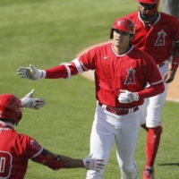 The Angels' Shohei Ohtani is congratulated by teammates after hitting a two-run home run against the Rangers in Tempe, Arizona, on Wednesday. | KYODO
