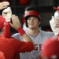 Angels starting pitcher Shohei Ohtani celebrates with teammates in the dugout after scoring against the Rangers in the sixth inning on Monday in Arlington, Texas. | USA TODAY / VIA REUTERS