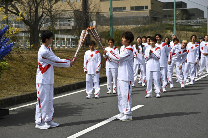 Azusa Iwashimizu (à droite au premier plan), membre de l’équipe japonaise de football féminin, transmet la flamme olympique à un lycéen, le 25 mars 2021 à Naraha, dans la préfecture de Fukushima.