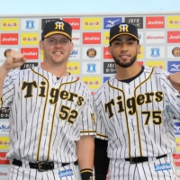 Tigers outfielder Jerry Sands (left) and pitcher Robert Suarez celebrate after a win over the BayStars at Koshien Stadium in Nishinomiya, Hyogo Prefecture, on Sunday. | KYODO