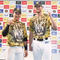 Tigers players Joe Gunkel (right) and Yusuke Oyama pose after their win over the Swallows at Koshien Stadium in Nishinomiya, Hyogo Prefecture, on Sunday. | KYODO
