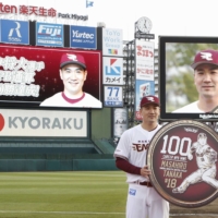 Rakuten pitcher Masahiro Tanaka holds up a placard celebrating his 100th win in Japan on Saturday at Sendai's Rakuten Seimei Park Miyagi. | KYODO