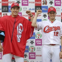 Carp pitchers Aren Kuri (left) and Haruki Omichi pose for photos after their win against the Giants on Saturday in Hiroshima. | KYODO