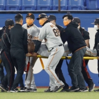 Giants outfielder Eric Thames is carried off the field on a stretcher after injuring his leg during the bottom of the third at Jingu Stadium on Tuesday. | KYODO