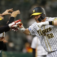 The Tigers' Jerry Sands celebrates with his teammates after giving Hanshin the lead with a solo home run in the eighth inning on Thursday at Koshien Stadium. | KYODO