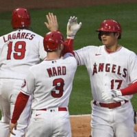 Angels designated hitter Shohei Ohtani (right) is congratulated by right fielder Taylor Ward (center) after hitting a two-run home run against Cleveland on Monday in Anaheim, California. | USA TODAY / VIA REUTERS
