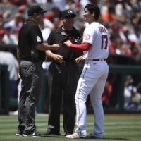 Angels pitcher Shohei Ohtani has his glove and hat checked by umpires after the fourth inning of Los Angeles' game against the Giants on Wednesday. | USA TODAY / VIA REUTERS