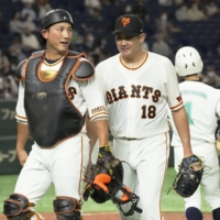 Yomiuri Giants pitcher Tomoyuki Sugano (right) walks off the field with catcher Seiji Kobayashi after the fourth inning against the Hokkaido Nippon Ham Fighters at Tokyo Dome on Sunday. | KYODO