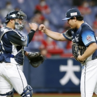 Seibu pitcher Kaima Taira celebrates with teammates Tomoya Mori after getting the save against Softbank on Monday in Osaka. | KYODO