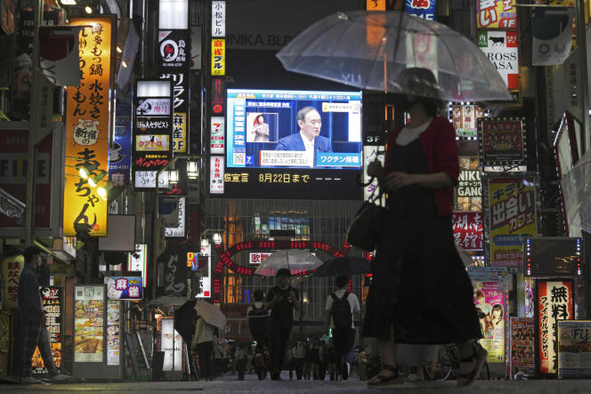 Des Japonais dans les rues de Tokyo où est retransmise l’allocution du premier ministre, Yoshihide Suga, sur l’instauration de l’état d’urgence en raison de la détérioration de la situation sanitaire liée au Covid-19, le 8 juillet.