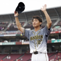 Hanshin pitcher Masashi Ito salutes visiting fans at Mazda Stadium after earning his fifth win against the season in Hiroshima on Saturday. | KYODO